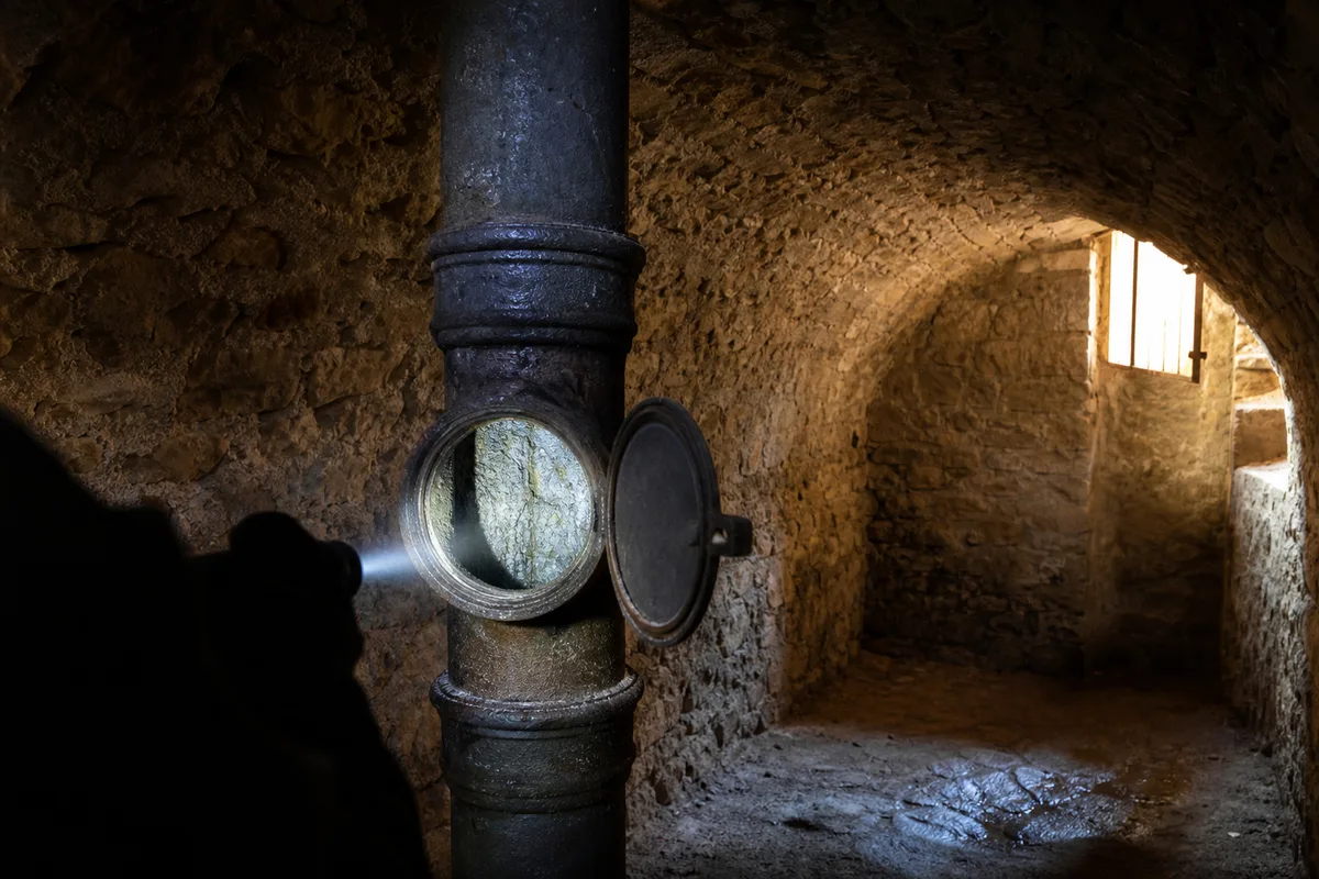 Colonne d’évacuation collective inspectée dans la cave d’un immeuble ancien du Roussillon